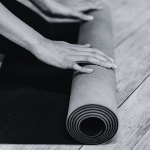 Hands unrolling yoga mat